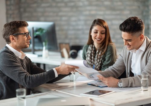 Happy couple signing a contract on a meeting with their real estate agent in the office.